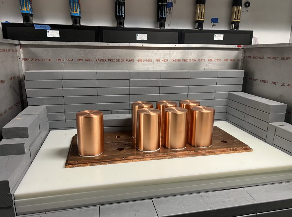 A set of copper cylinders sit within a partially-assembled shielding structure including lead and polyethylene plastic.